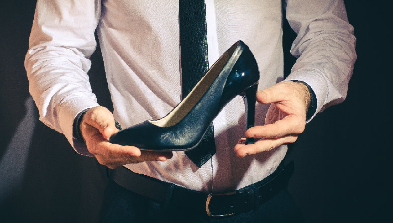 Businessmann hält schwarze High Heels in den Händen