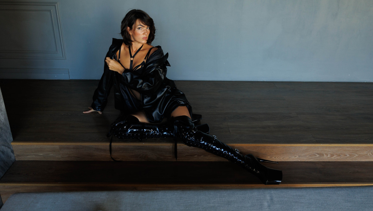 reife Frauen - sexy Brünetty sitzend in schwarzen Overknee Heels und schwarzer Lingerie