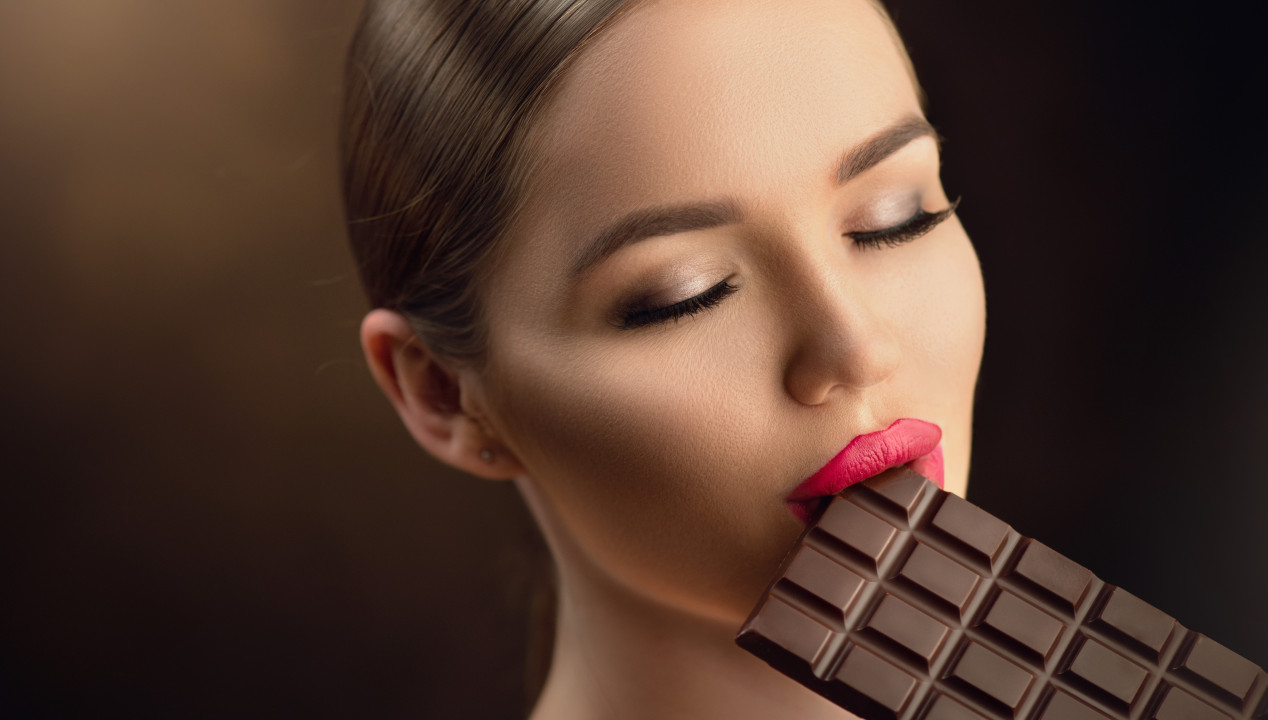 Sugardating Sugarbabe attraktive Frau mit rosa Lippenstift isst dunkelbraune Schokolade