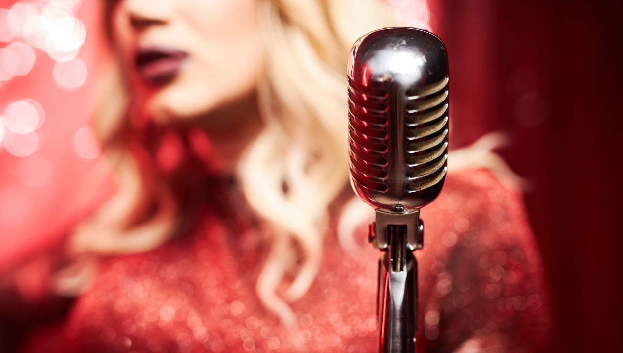 Dragqueen singt in rosa-rotem Kleid