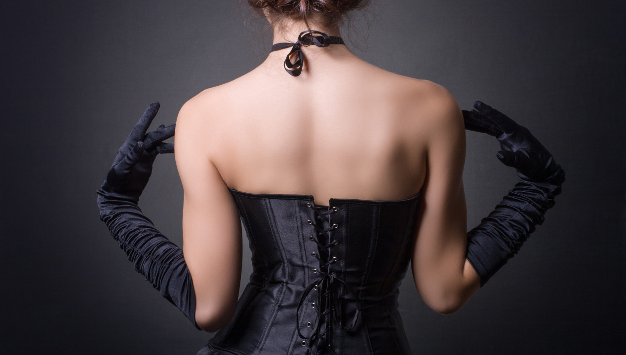 Eine Frau mit schwarzer Corsage präsentiert ihren nackten Rücken
